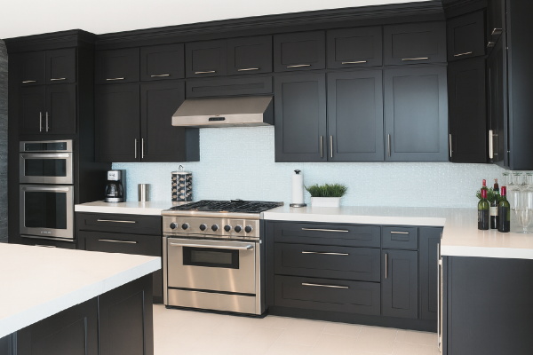Soft black cabinets with metallic hardware in a large kitchen with neutral colors.